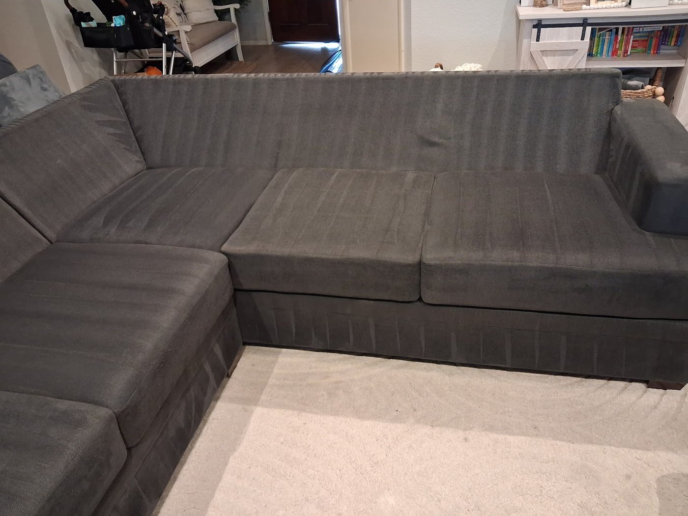 A dark gray sectional couch with fresh cleaning passes across the cushions