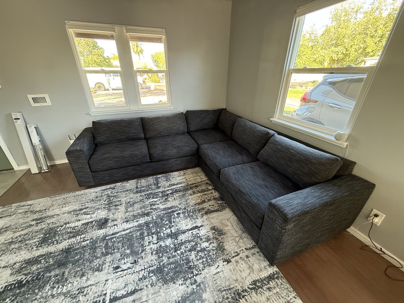 A dark gray sectional couch on a patterned area rug in a Tempe living room