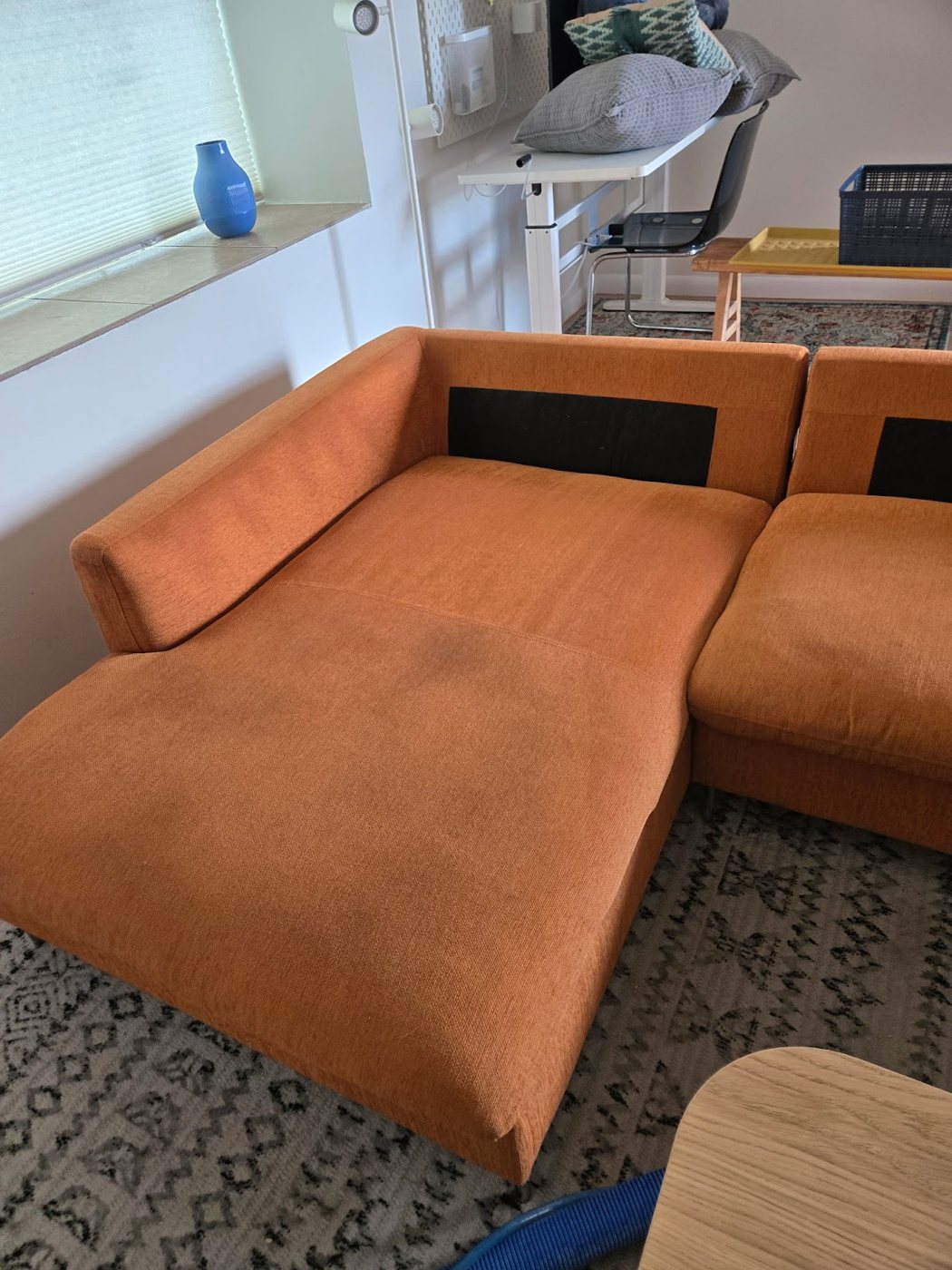 An orange sectional couch beside a patterned rug