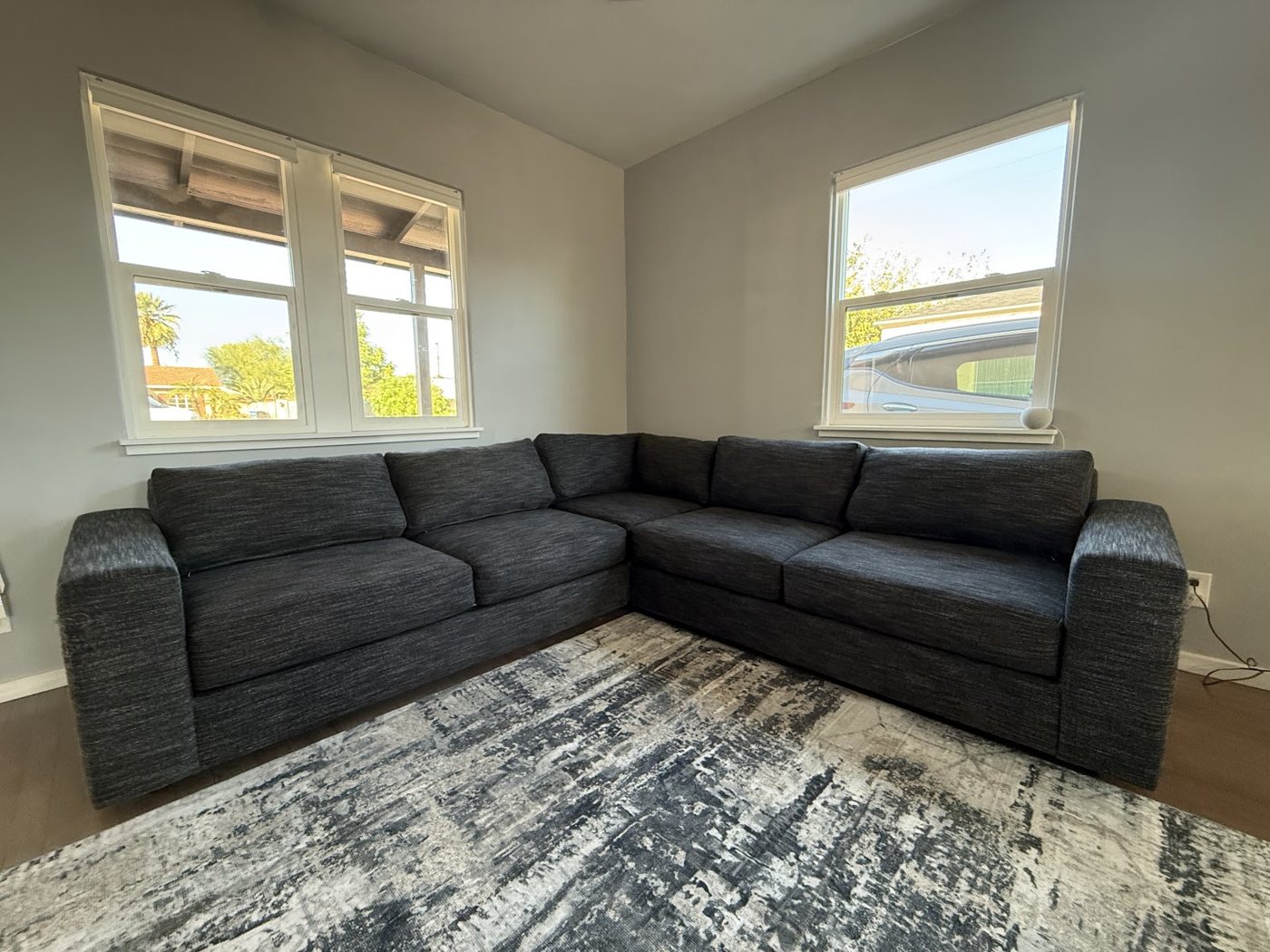 A gray sectional couch under two windows in a Tempe living room